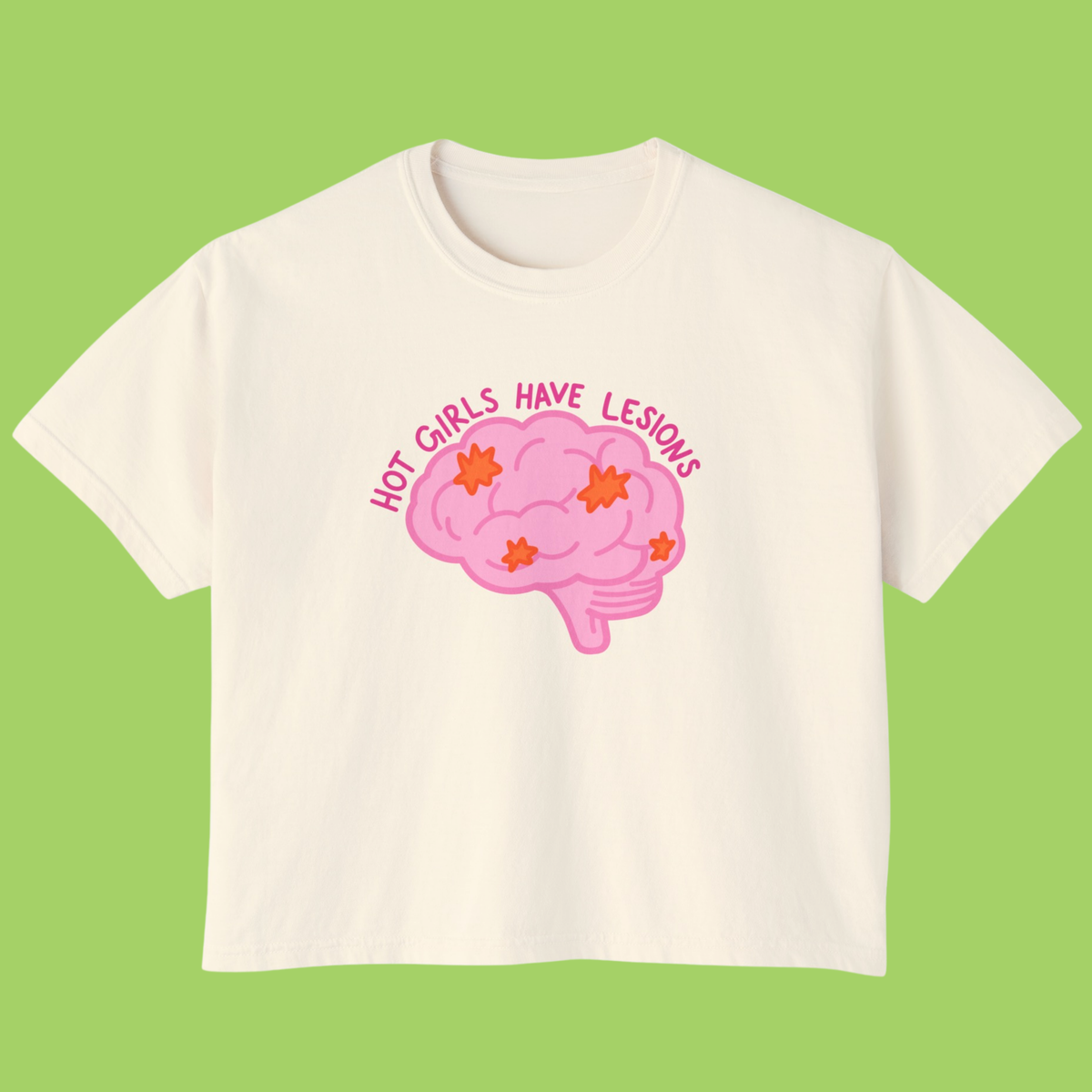 An off-white short-sleeve t-shirt with a pink cartoon brain graphic and the text 'HOT GIRLS HAVE LESIONS' in pink, displayed against a solid light green background.