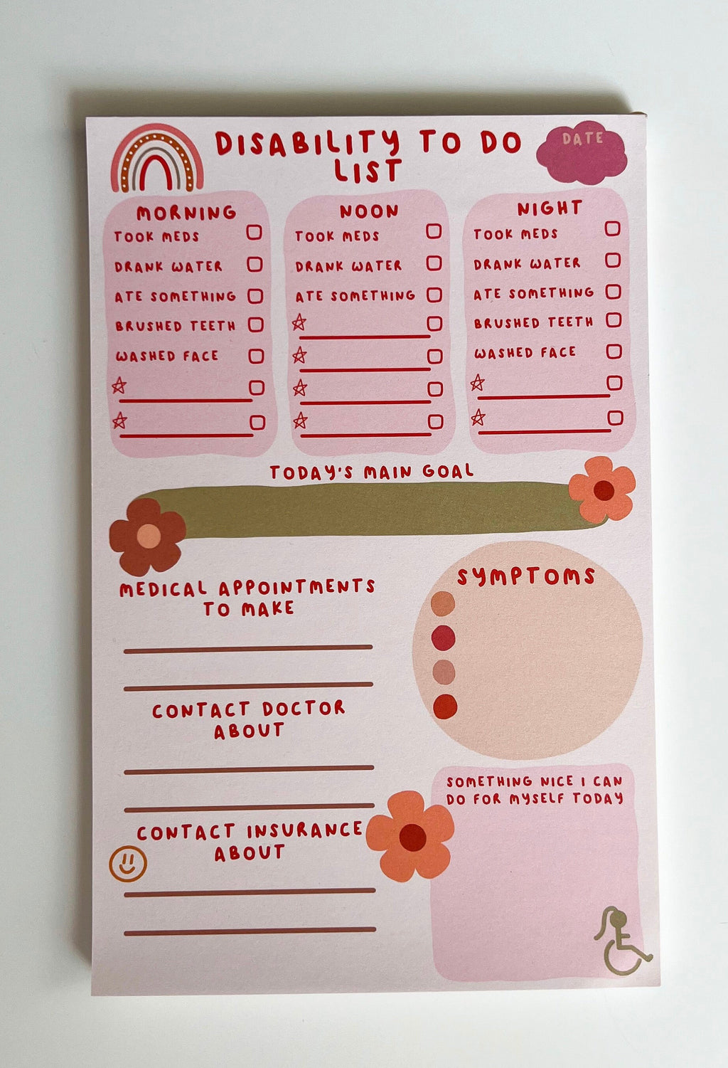 Disability To Do List Notepad with light colored sheets. Sections include: pink cloud to write the date down in, three pink boxes with red font reading "morning, noon, and night" with a checklist underneath them reading "took meds, drank water, ate something, brushed teeth, washed face" and a couple of empty spaces below to fill out yourself. There's a place to write down medical appointments to make, contact doctor about, and contact insurance about. There's a place to track symptoms. On white table